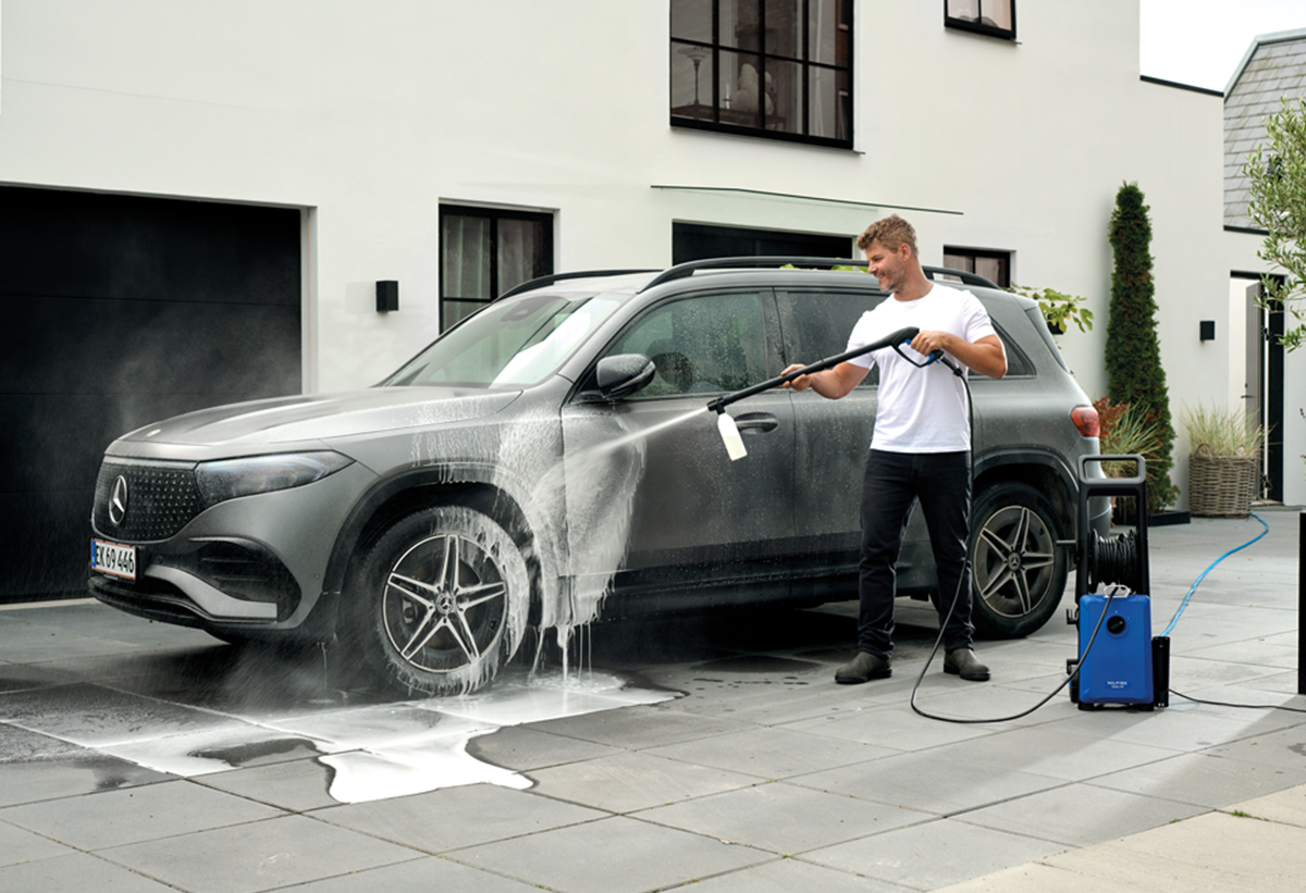 Απεικονίζεται άνδρας να χρησιμοποιεί το μηχάνημα για να πλύνει αυτοκίνητο.